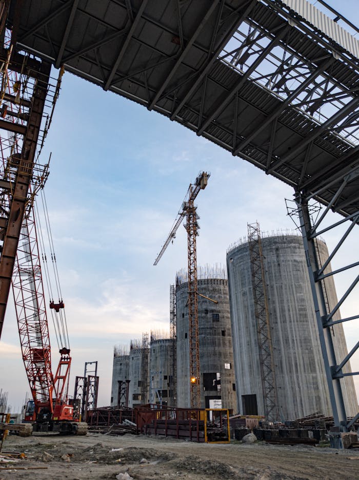 A detailed view of an industrial construction site in Bangladesh with silo structures and cranes.